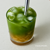 Layered iced matcha lemon tea with coconut jelly in a clear glass over ice, served with a metal straw.