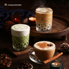 Cozy setup featuring three drinks made with Hakumori boba kits: matcha latte, milk tea, and spiced chai, surrounded by candles, pinecones, and wooden accents.